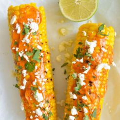 cropped image of 2 Grilled Corns Topped with Lime Butter and Crumble Feta Cheese, and Fresh chopped Coriander